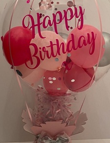 Happy birthday printed transparent balloon with pink and silver confetti stuffed balloons on a pink decorated box with 10 dairy milk chocolates